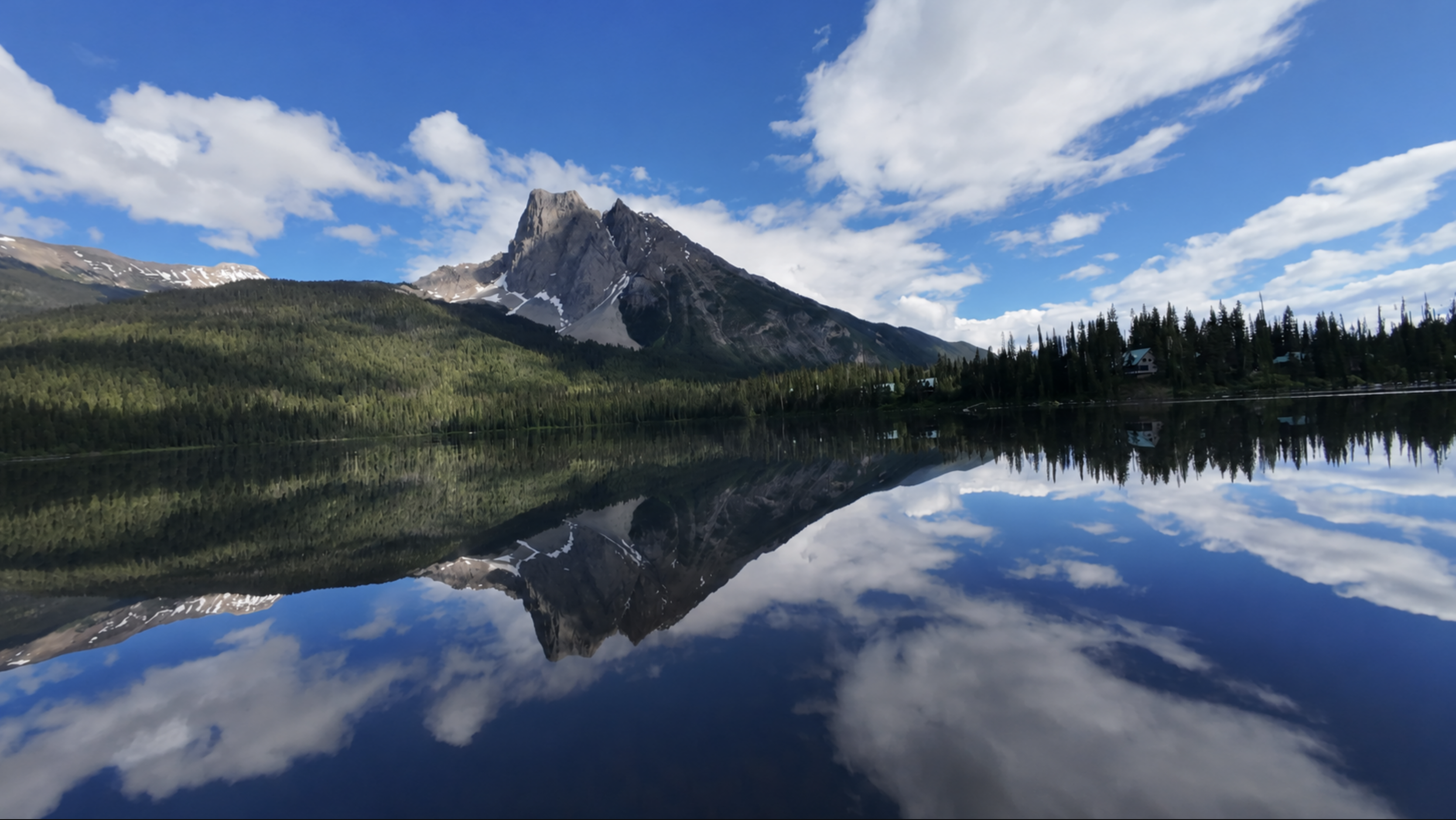 Picture of a mountain reflecting off of water with tress along side it.